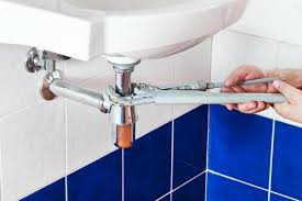 Plumber tightening a pipe fitting under a sink