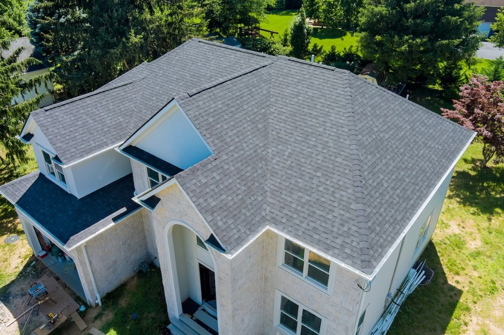 A large home with new black architectural shingle roofing viewed from above.